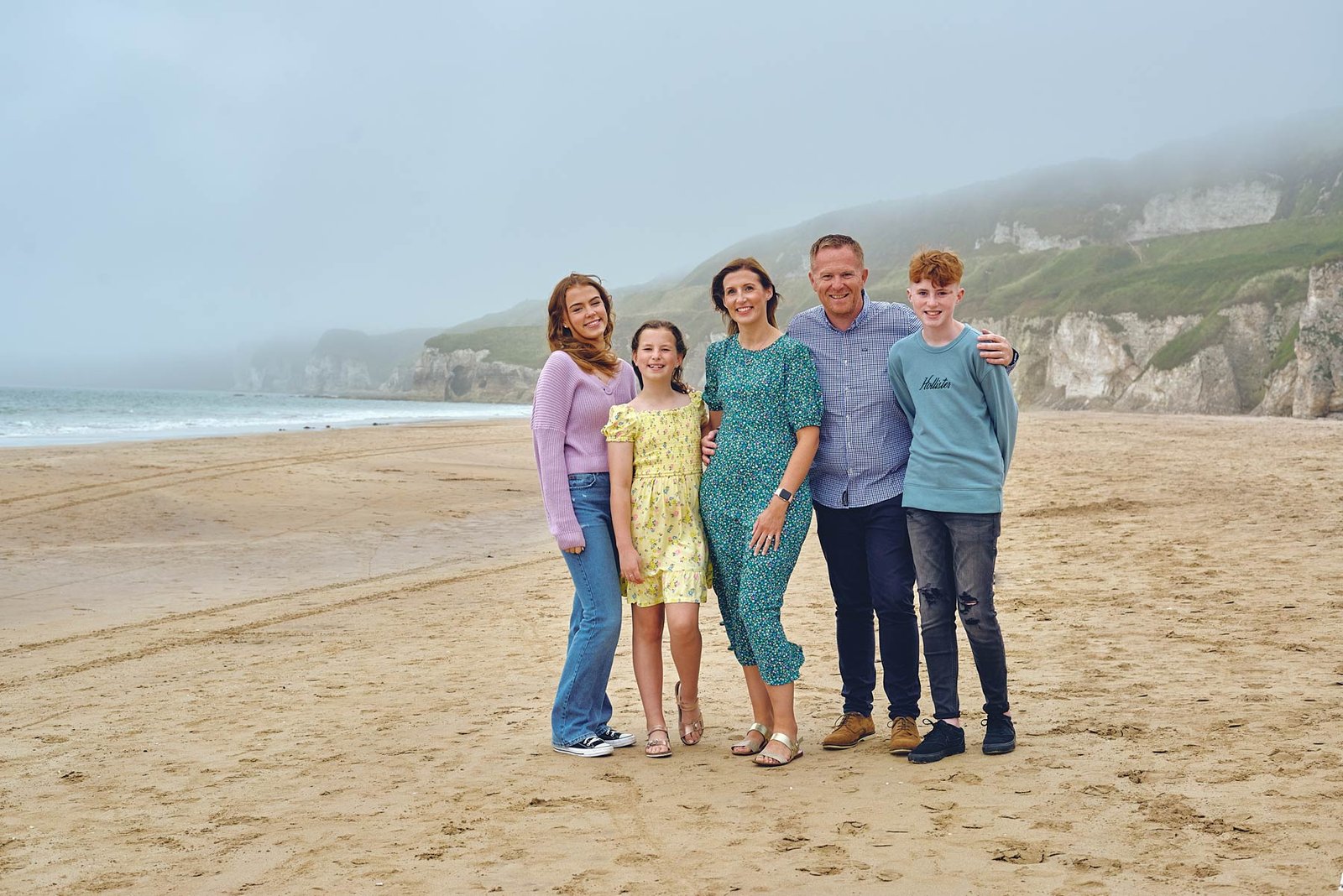 A family posing for a photo on a beach, captured by a photographer.