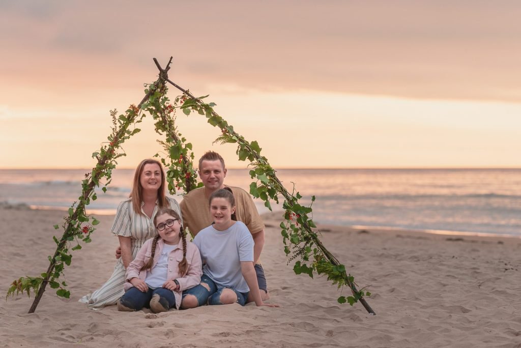 A Northern Ireland family poses on the beach with a teepee captured by NI photographers.