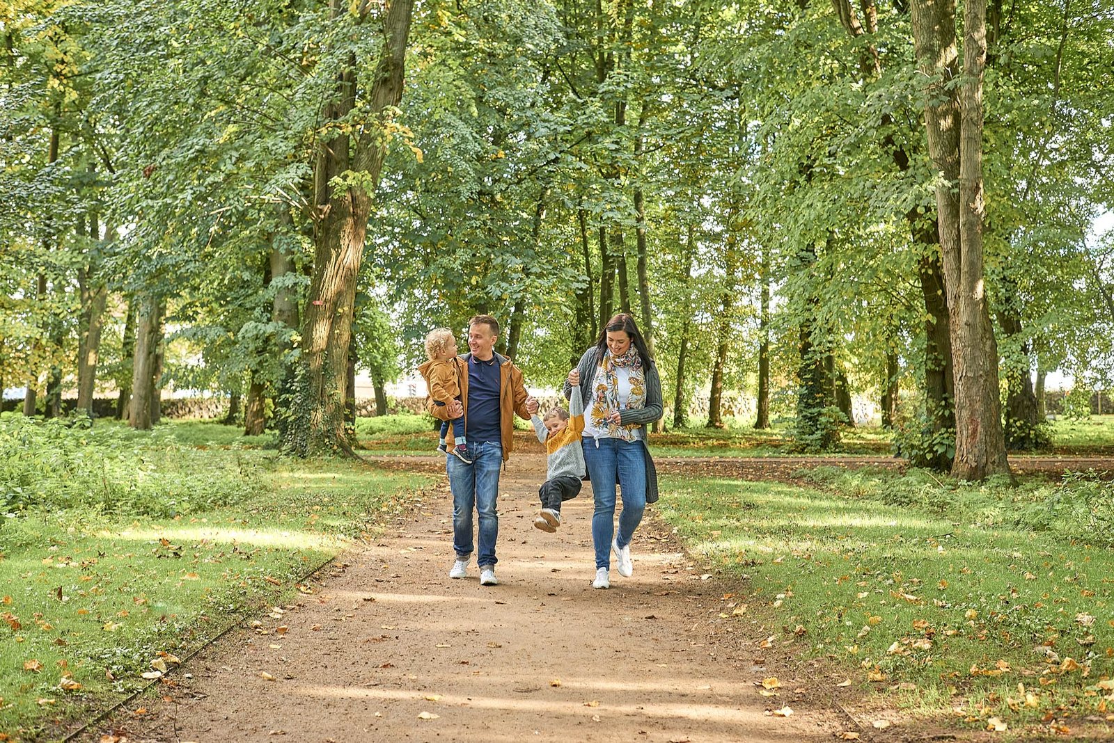 Two family photographers capturing moments of two people walking through a picturesque path in a park.