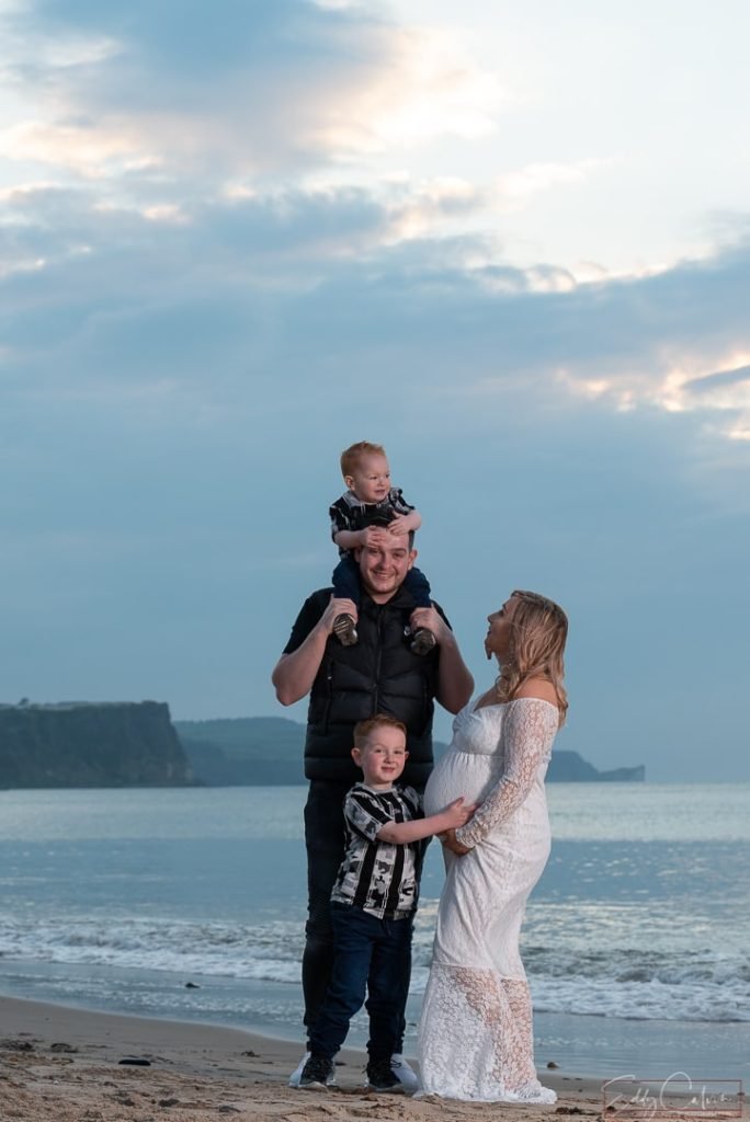 A family is captured by a photographer on the beach in Northern Ireland at sunset.