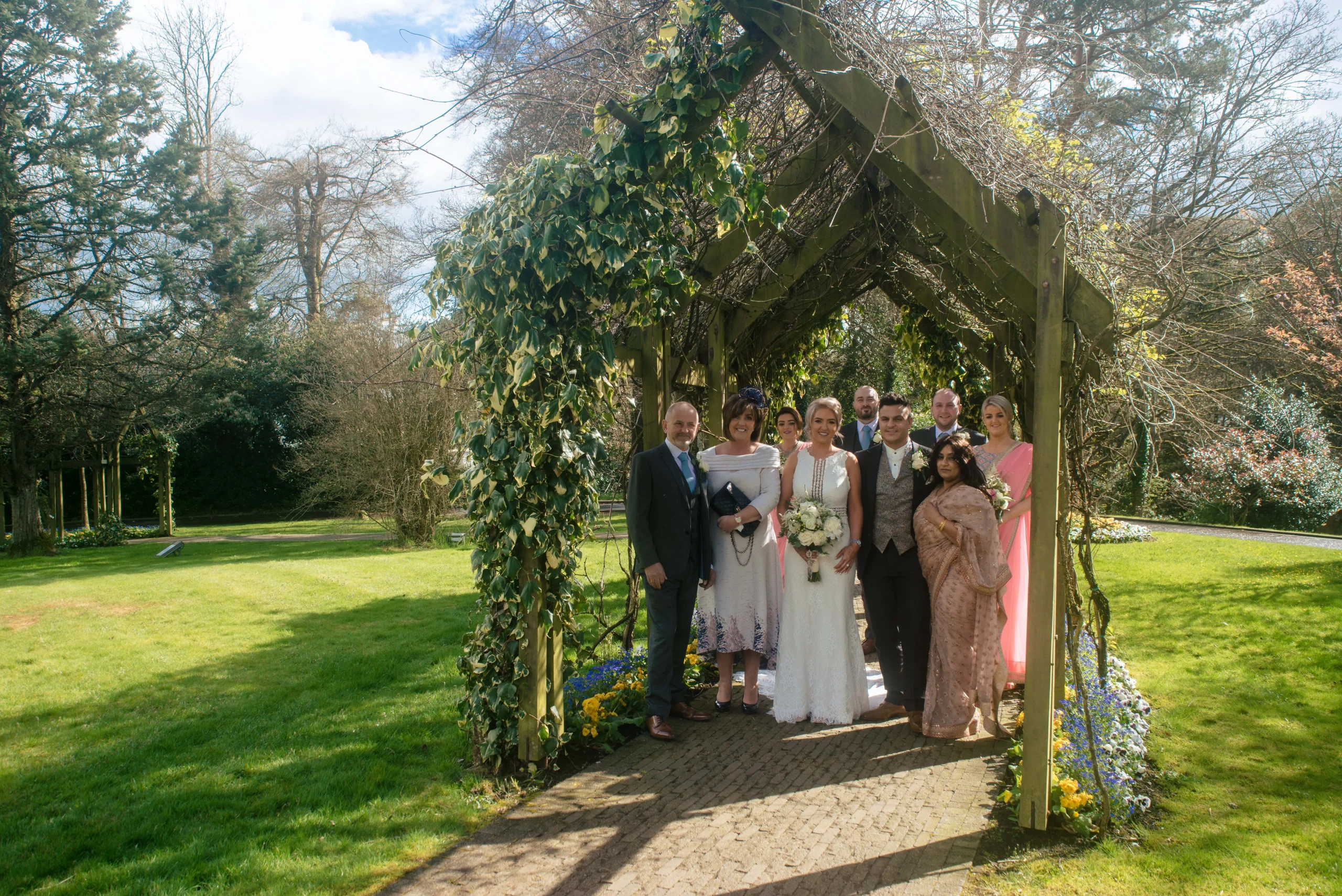 A family posing for a photo at a wedding party in a garden, captured by a Northern Ireland family photographer.