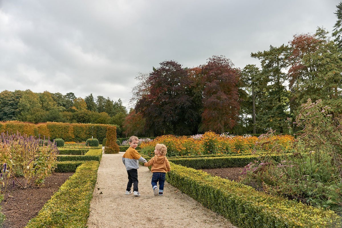 Two children walking down a path in a garden.