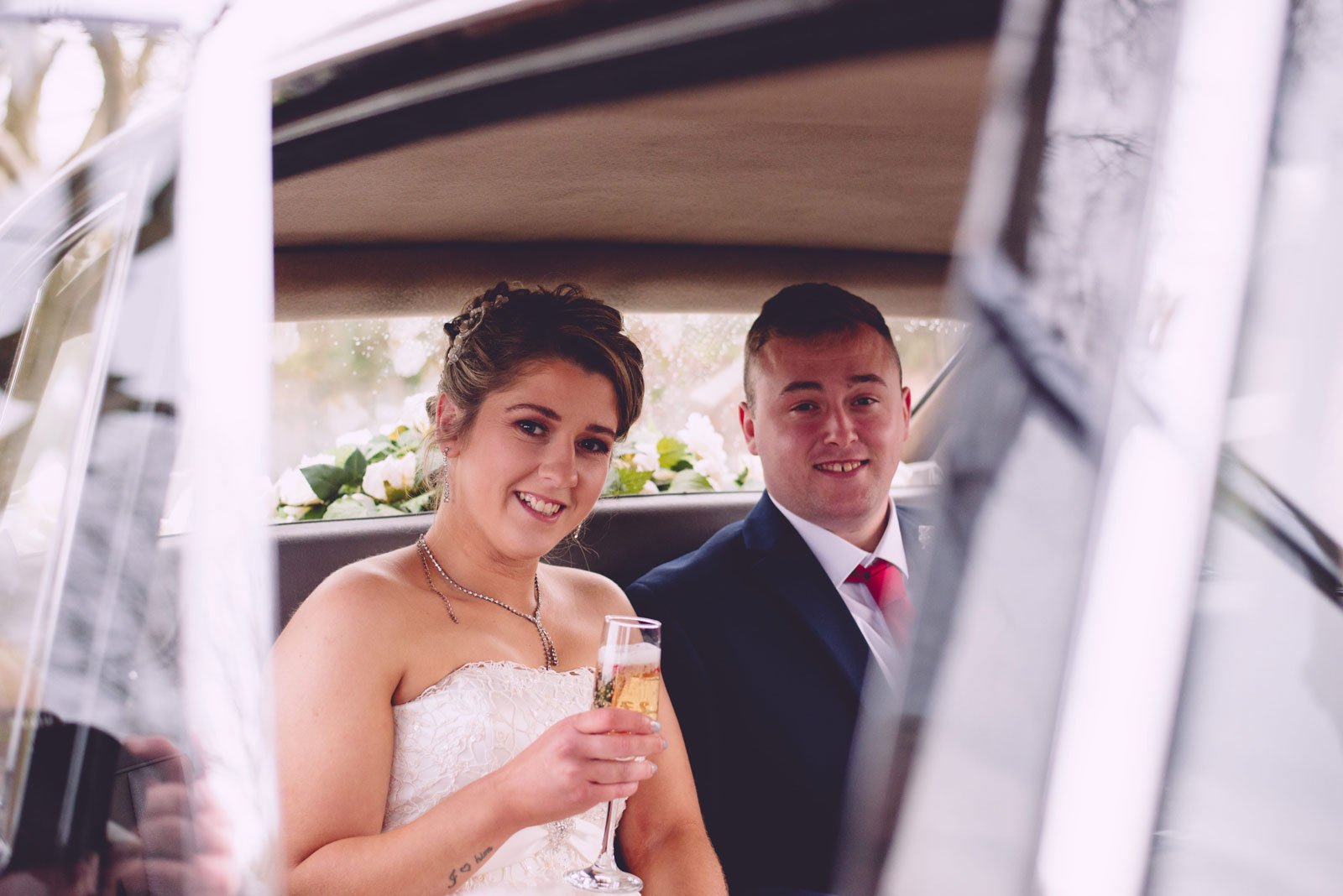 ballymoney family and wedding photographer A family photographer captures a bride and groom in the back seat of a car.