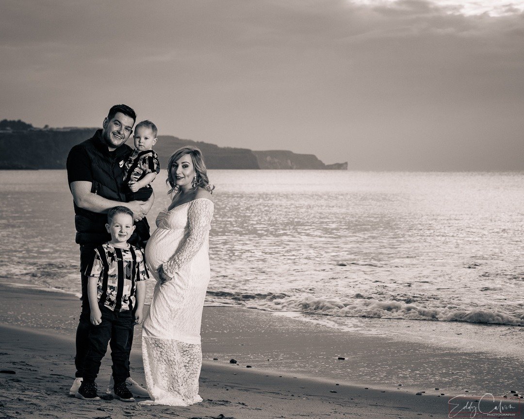 A family on the beach captured in black and white photography.