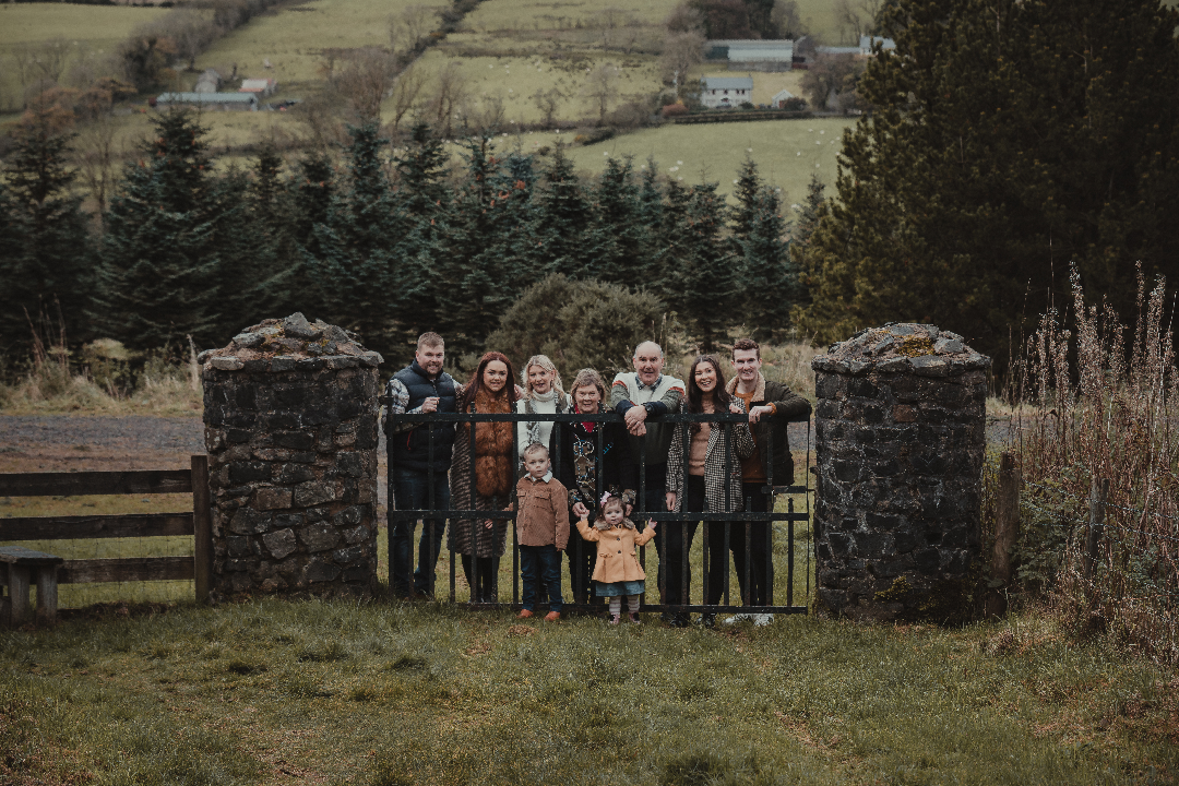 Family Photographer A family posing in front of a gate in the countryside.