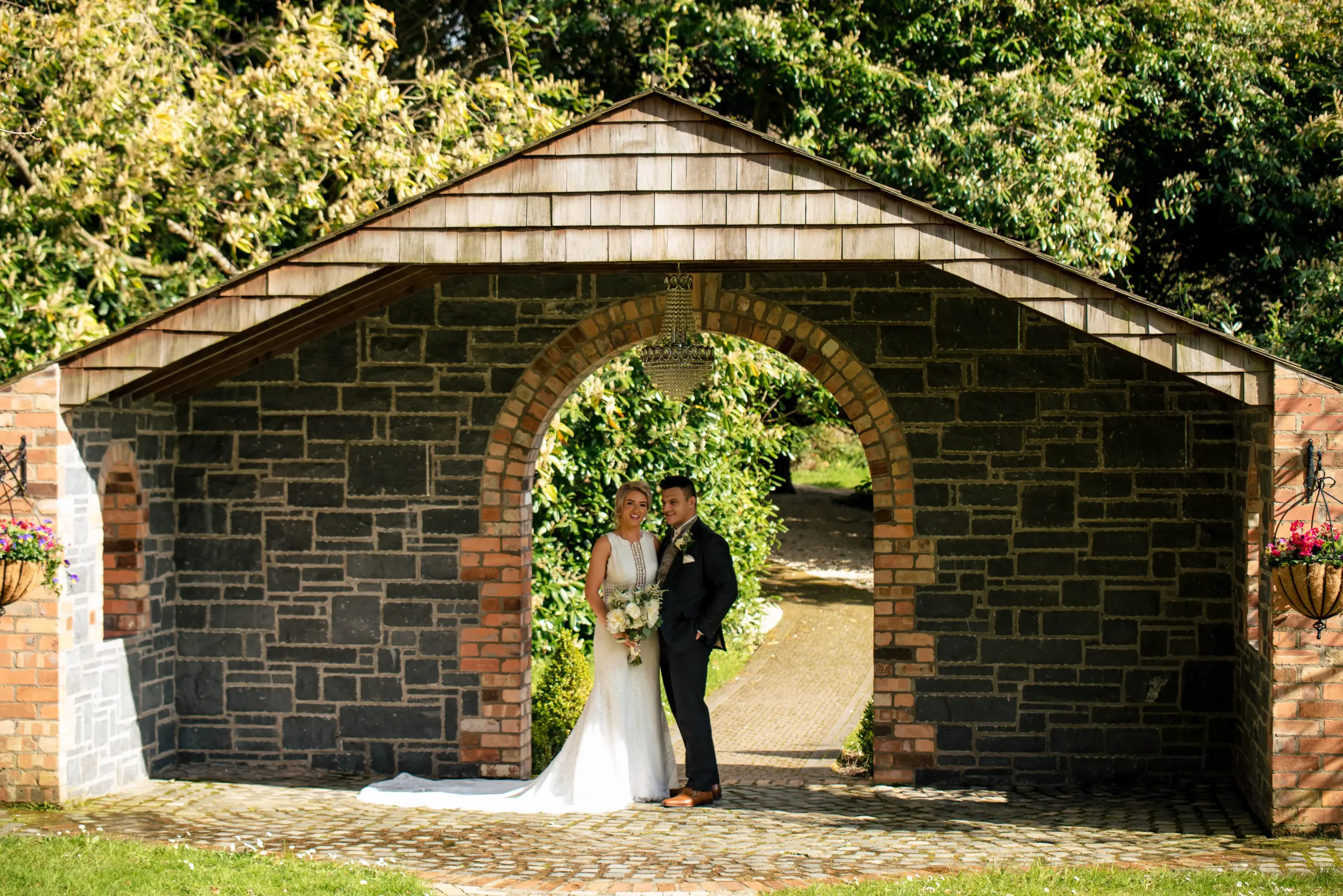 Family Photographer A bride and groom posing under a stone archway captured by a wedding photographer.