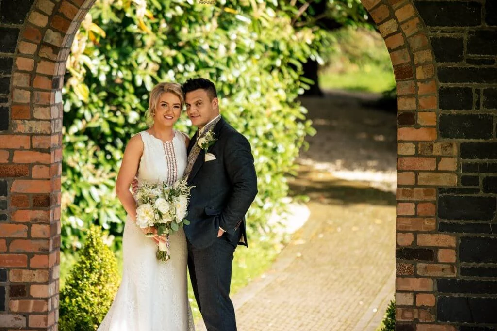 Family Photographer A bride and groom posing in an archway.