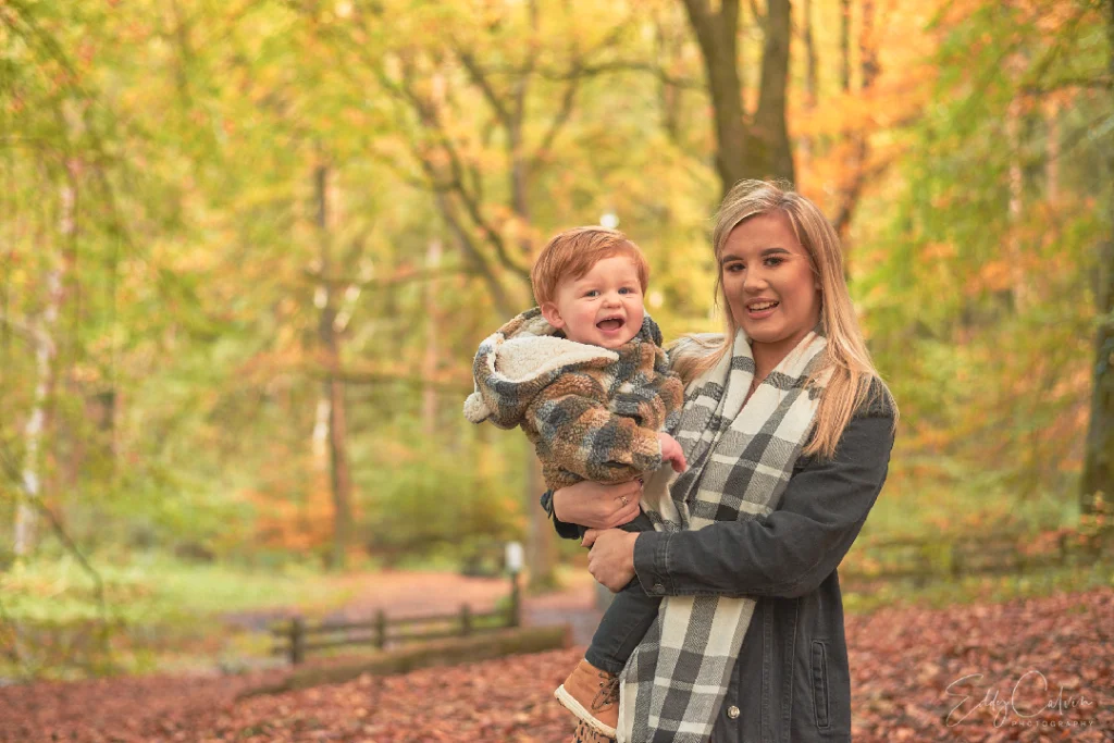 Family Photographer A woman holding a baby in an autumn forest.