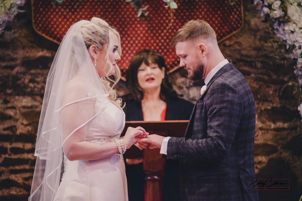 Family Photographer A bride and groom exchanging rings at their wedding ceremony.