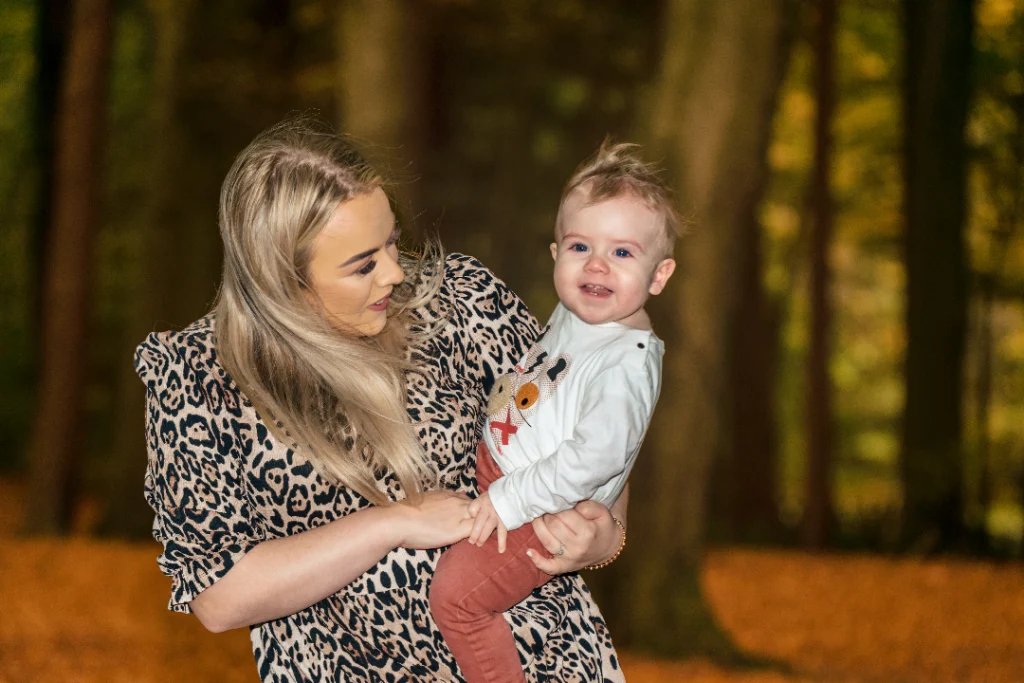 Family Photographer A woman holding a baby in the woods.